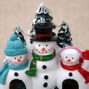 Detailed view of three resin snowmen characters on a festive Christmas music box ornament