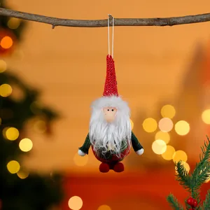 Adorable Christmas gnome fabric ornament hanging on a twig with festive bokeh lights.