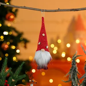 Detailed shot of a red knitted Christmas gnome ornament hanging on a rustic branch