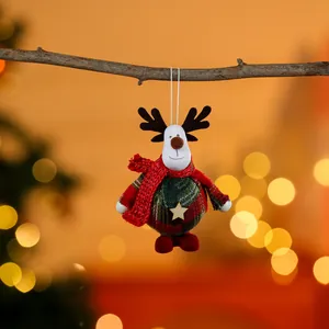 Plush reindeer Christmas ornament hanging on a tree branch with festive bokeh background