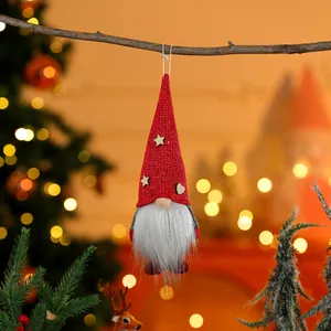 Handmade Christmas gnome ornament with red knitted hat hanging on a festive tree branch
