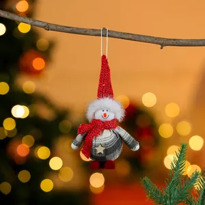 Close-up of a festive fabric snowman ornament hanging from a rustic tree branch