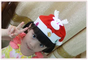 Detail view of a child wearing a red Christmas hat with a light-up reindeer