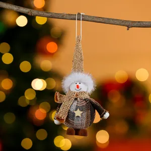 Close-up of fabric Christmas snowman ornament hanging on a twig with warm bokeh lights