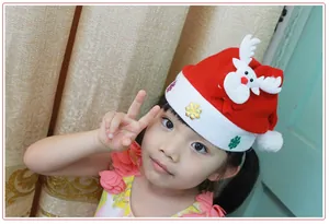 Cute child wearing a red Christmas hat with a festive reindeer and snowflake decoration.