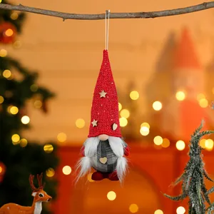 Close-up detail of a red knitted Christmas gnome ornament hanging from a dry tree branch.