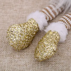 Close-up detail of sparkling gold sequin feet and soft white faux fur on a Christmas gnome doll.