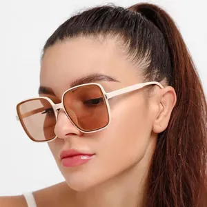 Modieuze oversized vierkante zonnebril met beige montuur gedragen door een model