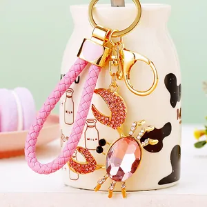 Gold-tone crab keychain with pink rhinestones and a stylish braided strap bag charm