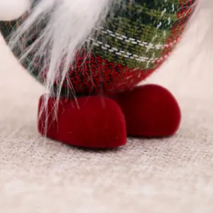 Nahaufnahme von Weihnachtsgnom-Deko mit roten Samtfüßen und kariertem Stoffmuster.