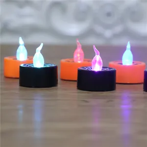 Close-up of LED Halloween tea lights with glowing flame-shaped bulbs on wooden table