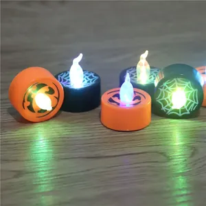 Detailed macro view of Halloween LED tea lights featuring pumpkin and spider web patterns