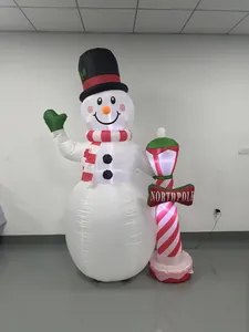 Aufblasbarer Weihnachtsschneemann mit North Pole Schild und einer bunten Zuckerstangen-Laterne.