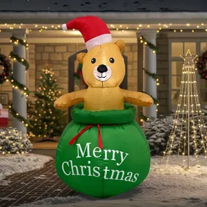 Détail d'un ours de Noël gonflable sortant d'un sac cadeau vert dans un jardin enneigé