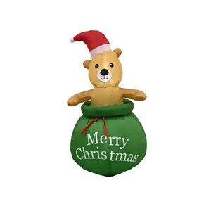 Ours de Noël gonflable sortant d'un sac cadeau vert avec un texte de joyeuses fêtes