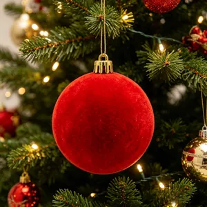Dettaglio di una pallina di Natale floccata rossa appesa a un ramo di pino festivo