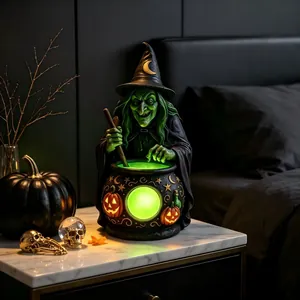 Détail d'une sorcière d'Halloween en résine remuant un grand chaudron vert lumineux.