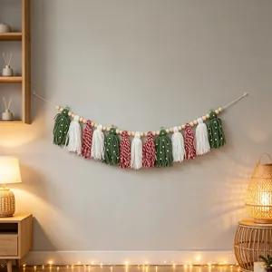 Handmade Christmas tassel garland hanging on a neutral wall in a warm cozy room setting