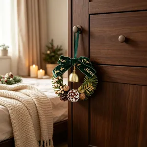 Kleine kerstkrans met fluwelen strik en gouden bel hangend aan een houten lade