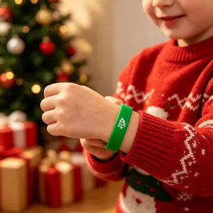 Detailopname van een kind met een groene kerst-siliconenarmband met witte kerstboom