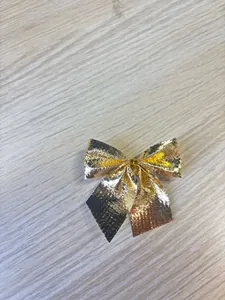 Detailed view of a mini golden metallic bow for Christmas tree DIY crafts and decoration.