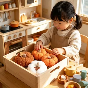 Handcrafted soft knit pumpkin decorations in a wooden crate shown with a child playing.