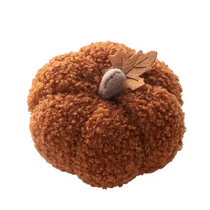 Close-up macro view of a soft plush bouclé pumpkin decoration with a brown felt leaf