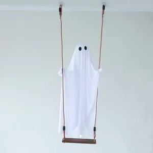 Adorable white Halloween ghost hanging ornament on a wooden swing against white wall