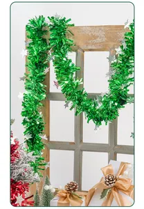 Green Christmas tinsel garland with silver stars hanging on a rustic wooden window frame
