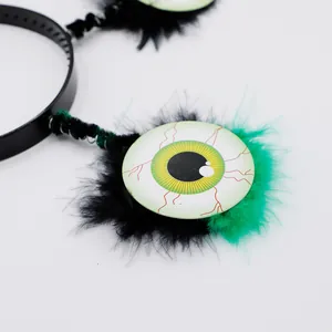 Détail macro du serre-tête d'Halloween œil vert avec plumes noires et vertes.