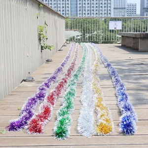 Colorful Christmas tinsel garlands displayed on a wooden deck for festive outdoor decor.