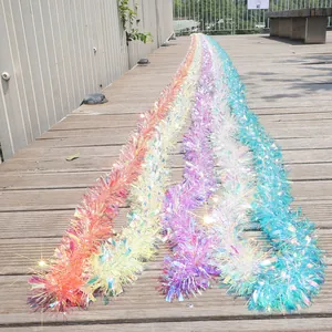 Close-up of long iridescent Christmas tinsel garlands on a wooden outdoor deck.