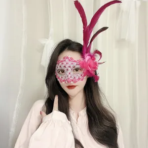 Detailansicht einer rosa Spitzen-Maskerade-Maske mit Federn und Blume an einer Frau