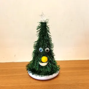 Close-up detail view of a cute cartoon electric Christmas tree toy with soft tinsel texture.