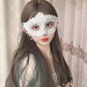 Detailed view of a white lace masquerade mask with rhinestone detailing worn by a model.