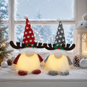Pair of lighted Christmas gnomes with reindeer antlers on a snowy winter windowsill