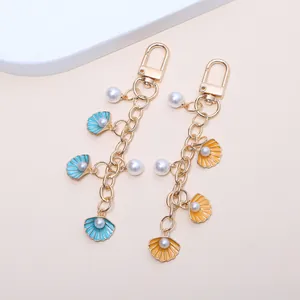 Détail rapproché de porte-clés coquillage et perles imitation avec finition dorée élégante