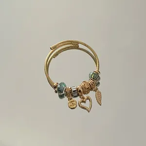 Detailed shot of an adjustable gold-tone steel charm bracelet with heart and leaf pendants