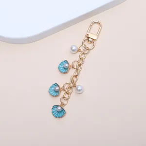 Vue détaillée d'un porte-clés océan avec des coquillages émaillés bleus et perles.