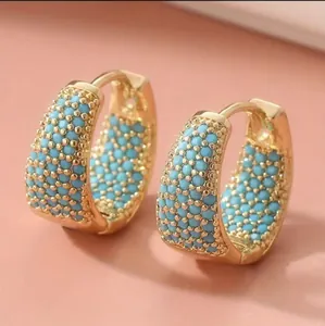 Dettaglio ravvicinato di orecchini a cerchio placcati in oro 18K con perline turchesi