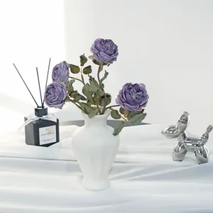 Detailed view of purple artificial roses in white vase with elegant home decor props