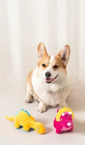 Perro Corgi jugando con peluches de dinosaurio amarillo y rosa para mascotas en alfombra
