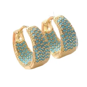 Orecchini a cerchio placcati oro 18K con pavé di pietre turchesi su sfondo bianco