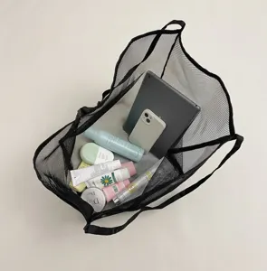 Grande borsa in rete nera riempita con vari articoli da toeletta e dispositivi elettronici