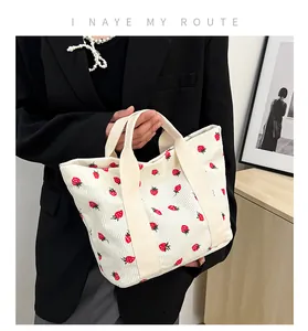 Detailed close-up of a white corduroy tote bag featuring a cute strawberry print