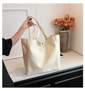Detailed side view of a cream canvas tote bag with side pockets and sturdy straps