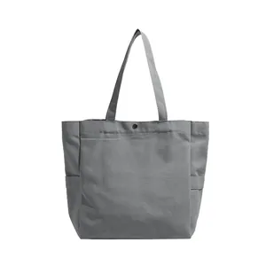 Detailed view of a minimalist grey canvas tote bag featuring a durable snap button closure