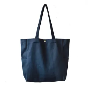 Minimalist navy blue canvas tote bag with side pockets and gold snap button detail.