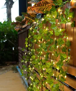 Detailansicht von LED-Efeulichterketten, die an einem hölzernen Gartenzaun leuchten