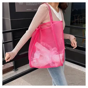 Dettaglio di una grande borsa portaoggetti in rete rosa portata in un contesto urbano
